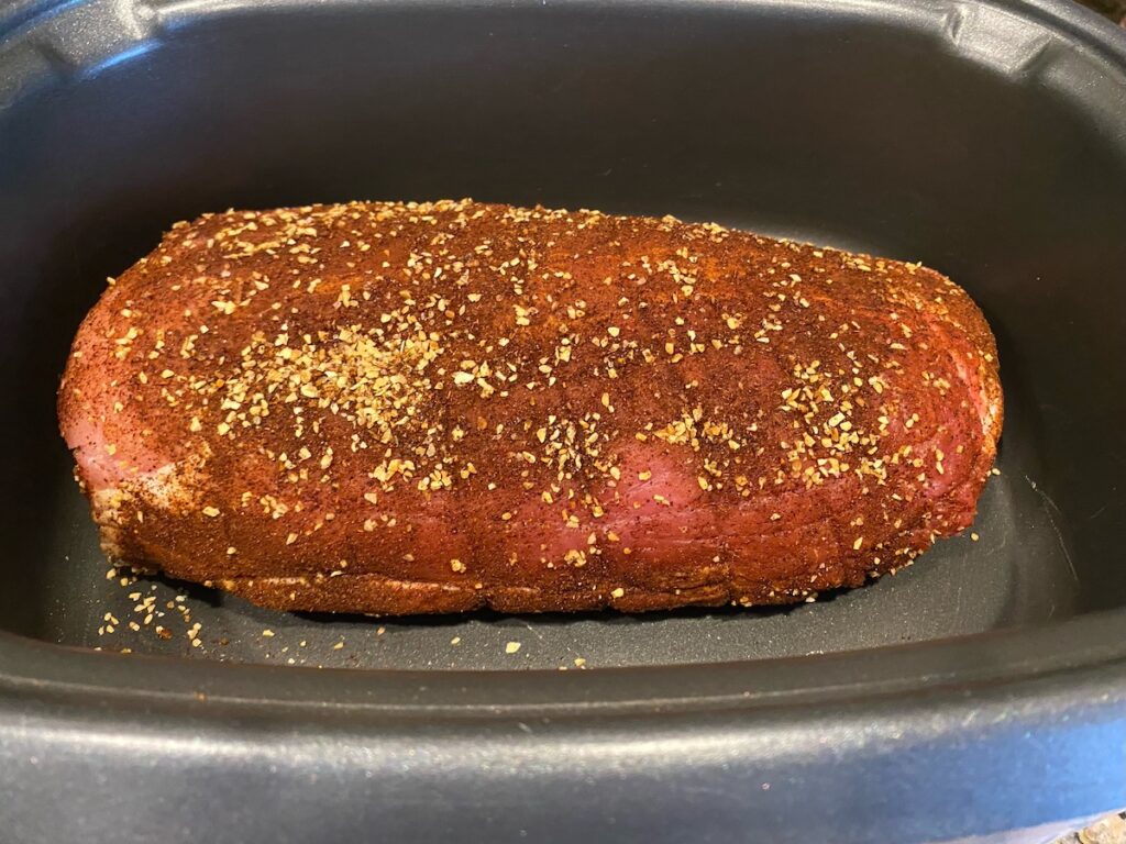 image shows pork shoulder in a slow cooker