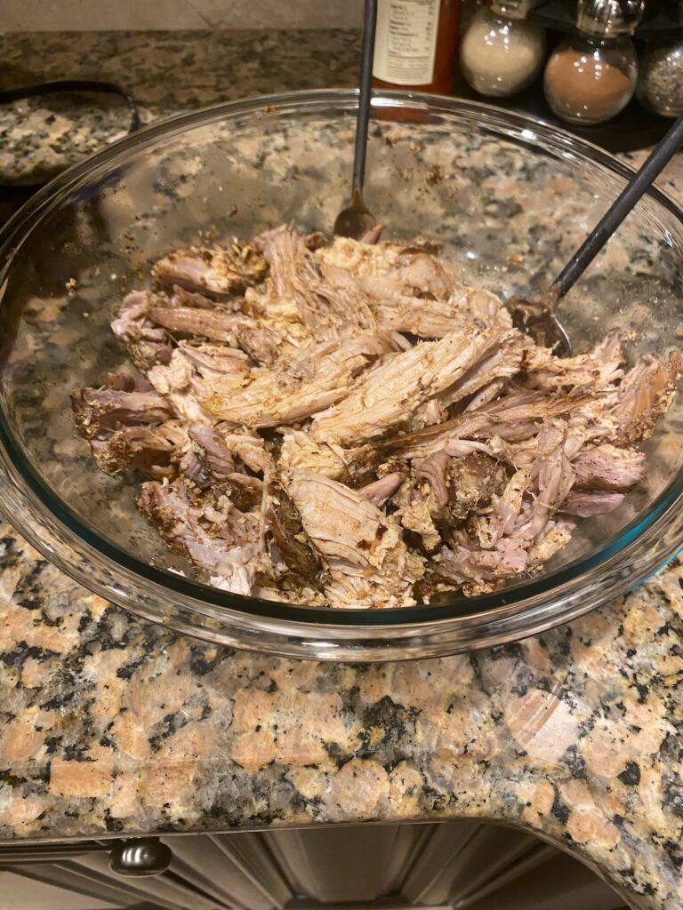 image shows pulled pork shoulder bbq shredded in a glass bowl