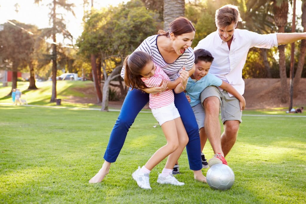 family playing soccer at a park, practicing healthy family activities