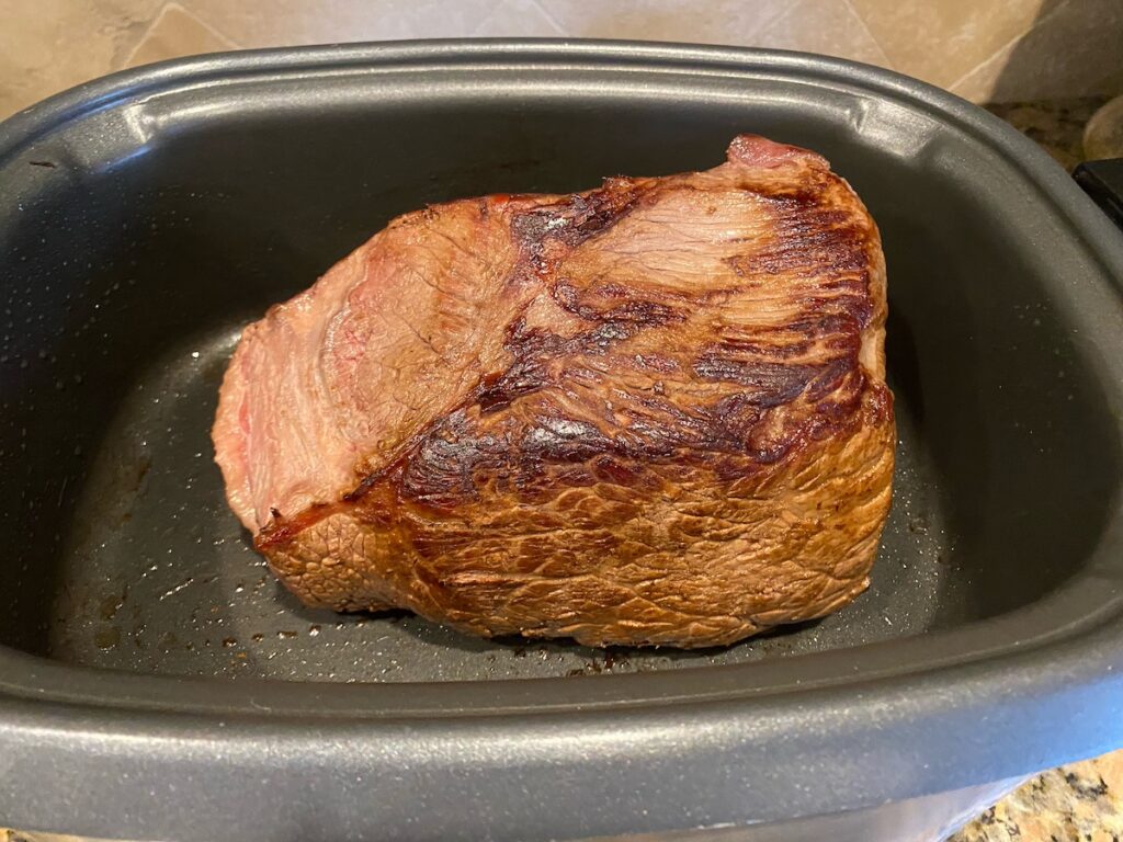 image shows Italian pot roast browned in slow cooker