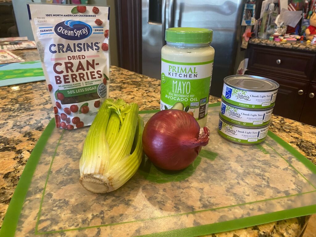 ingredients for cranberry tuna salad recipe shown on kitchen island - dried cranberries, celery, onion, mayo, and canned tuna