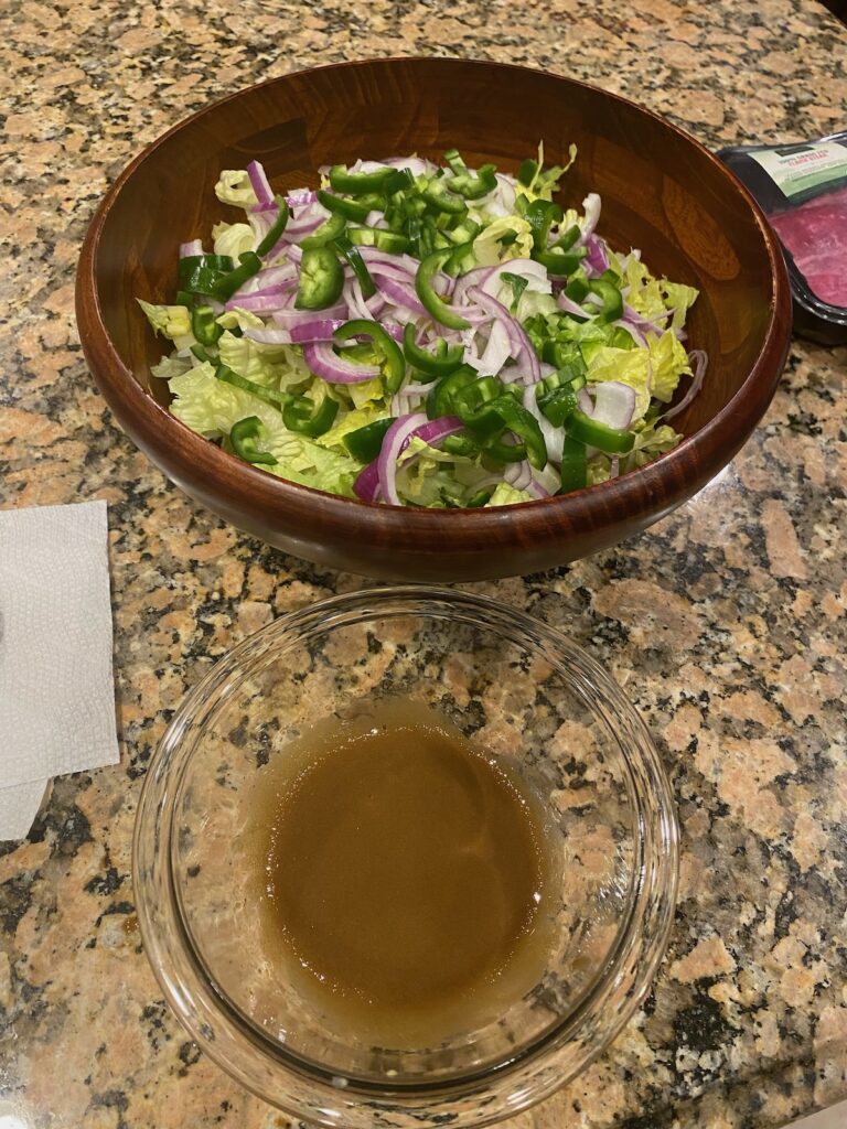 image shows salad veggies in one bowl and homemade dressing in a small glass bowl