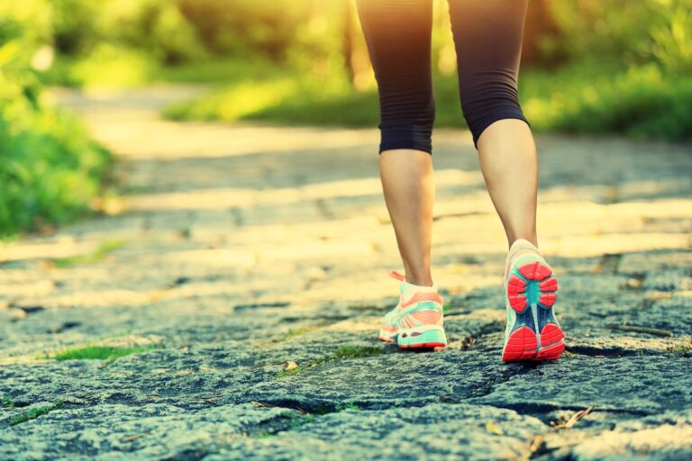 image shows woman walking outside on a trail, who knows the benefits of walking for moms