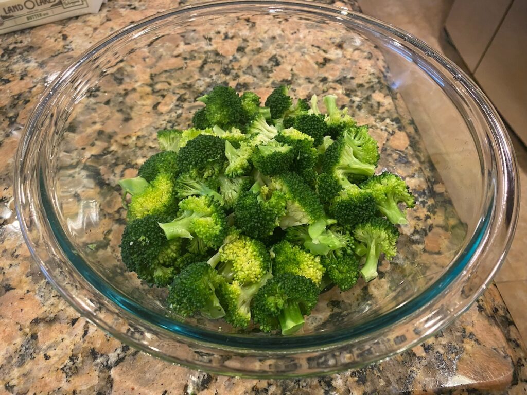 image shows cooked broccoli in a glass bowl