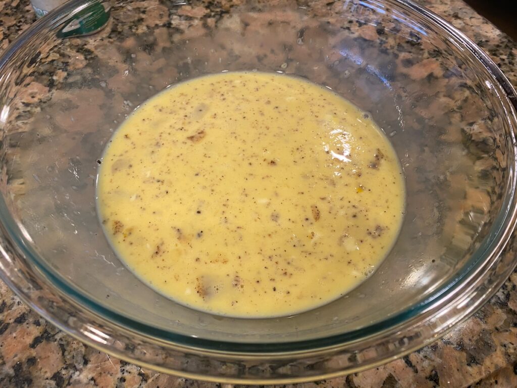 image shows egg, coconut milk, melted butter, nutmeg, salt, and pepper after whisking step.