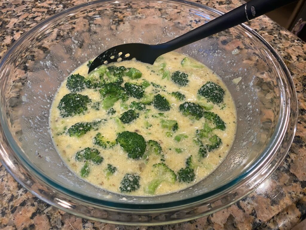 image shows broccoli and cheese stirred together with the liquid ingredients for the crustless broccoli quiche