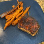 image shows finished spice-rubbed grilled pork chops and carrots meal on a dish