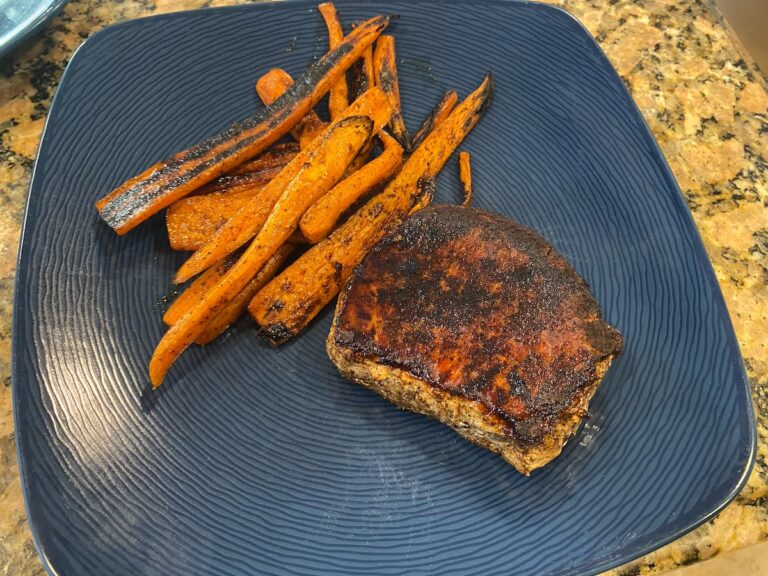 image shows finished spice-rubbed grilled pork chops and carrots meal on a dish