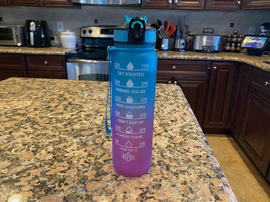 image shows blue and purple motivational water bottle with time marker on kitchen island