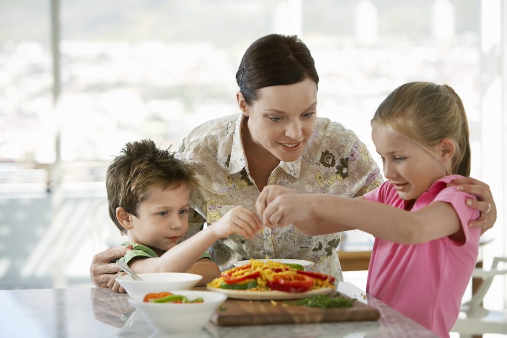 image shows mother preparing meal with two children, one of the healthy family habits in our list