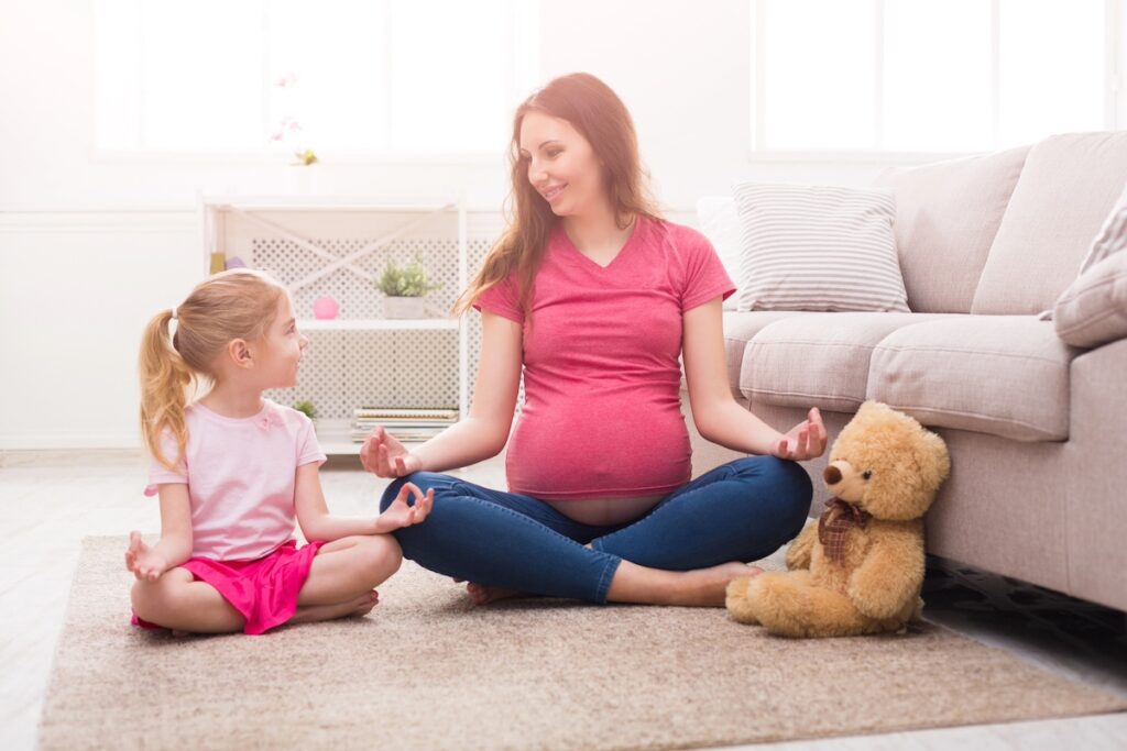 image shows pregnant mother practicing yoga and meditating with daughter, mindfulness, healthy family habits