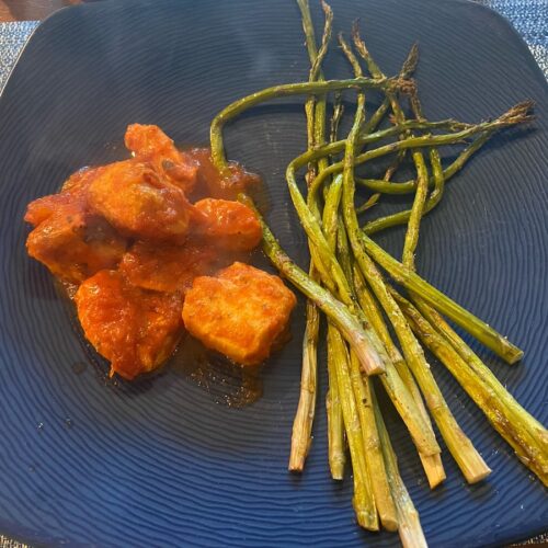 cooked slow cooker Italian chicken meal with roasted asparagus on dinner plate