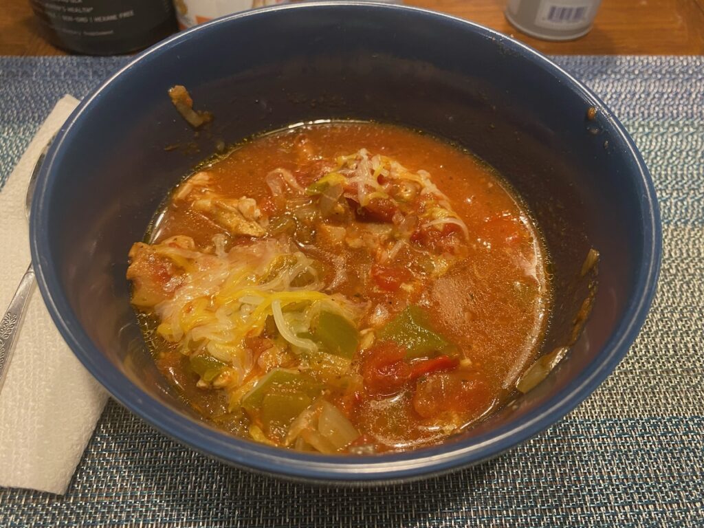 image shows slow cooker no bean chili served in bowl with shredded cheese