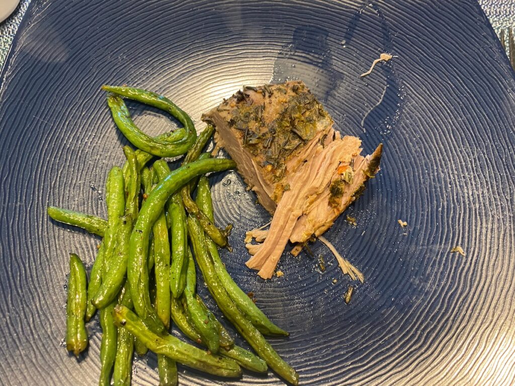 image shows slow cooker herbed pork roast on dinner plate with string beans