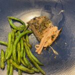 image shows slow cooker herbed pork roast on dinner plate with roasted string beans