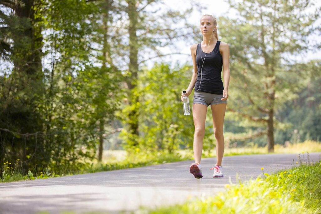 image shows woman walking outdoors, one of the low-impact workouts for moms