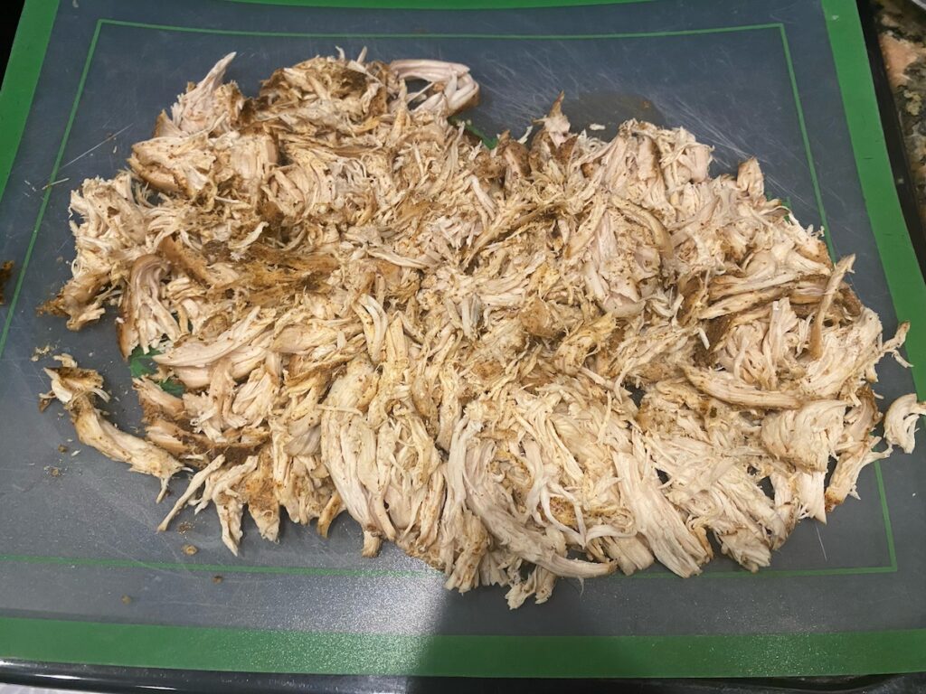 image shows shredded chicken on a cutting board