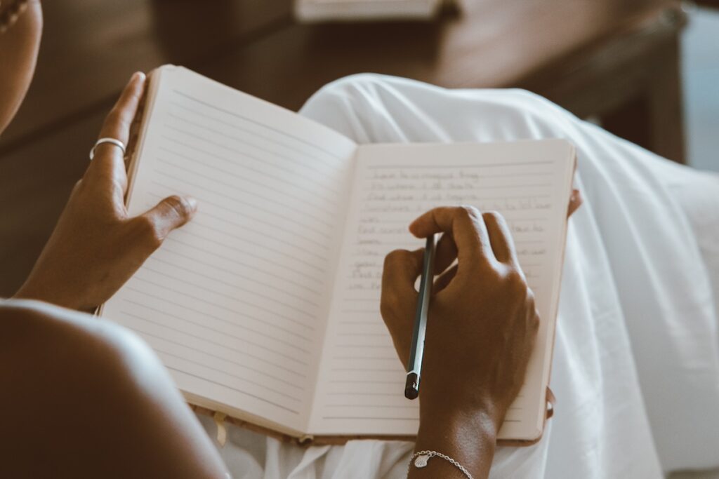 close-up of woman writing in gratitude journal for mental health, holding pen