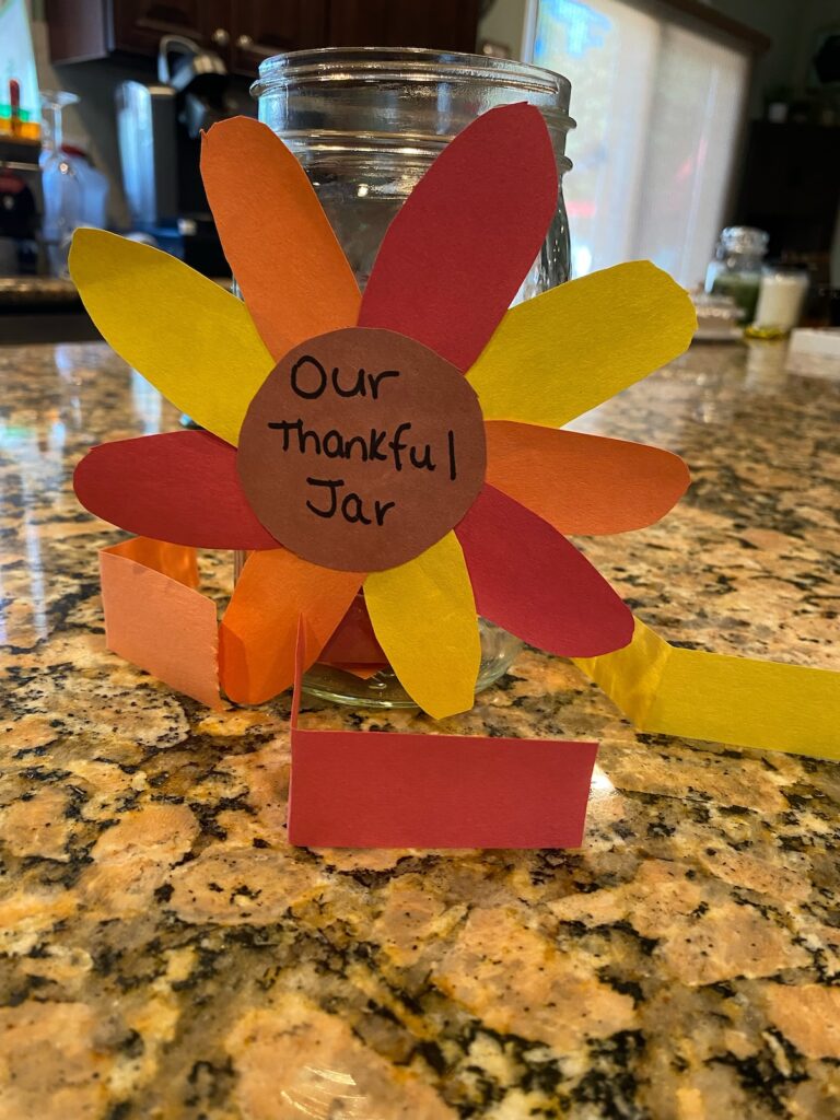 thankful jar on kitchen island with red, yellow, and orange slips of paper