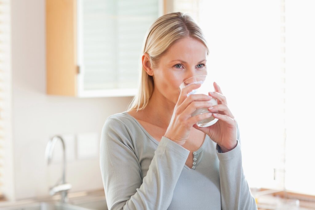 Woman drinking water to stay hydrated and reduce sugar cravings