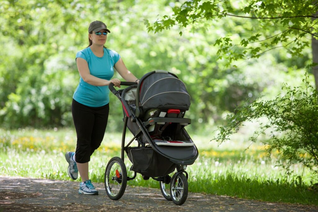 Mom walking briskly with stroller outdoors, demonstrating cardio workouts for busy moms.
