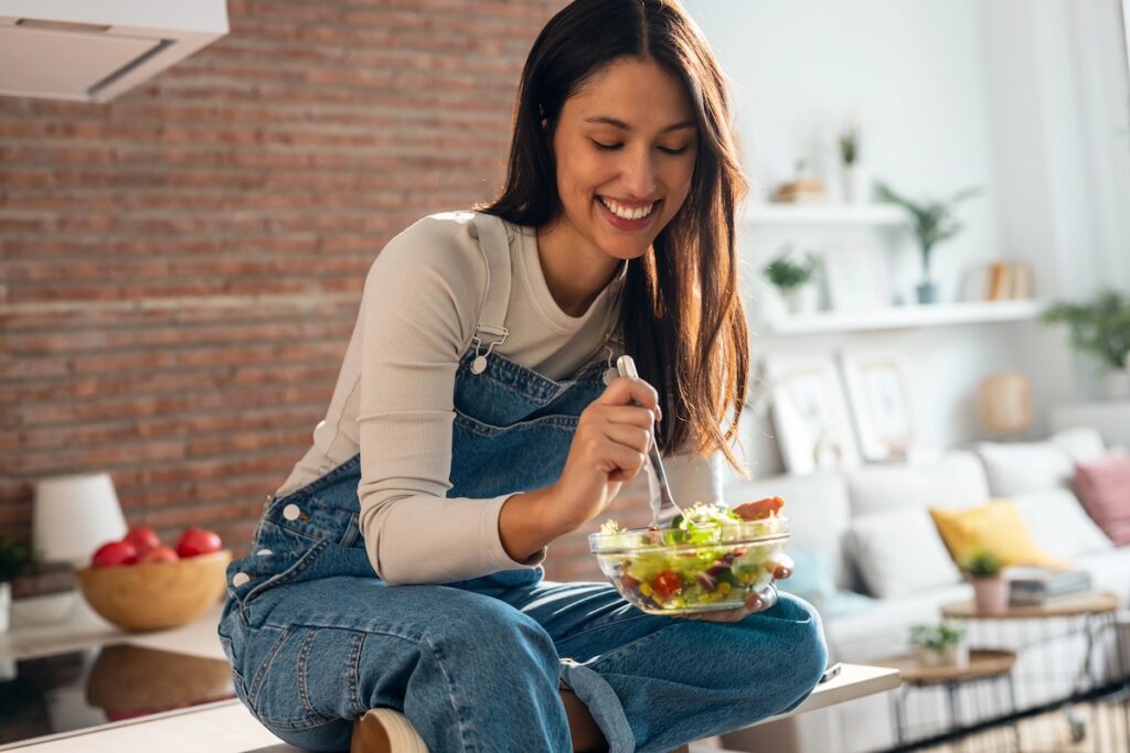 busy mom in her 40s smiling in kitchen with healthy food, positive food mindset