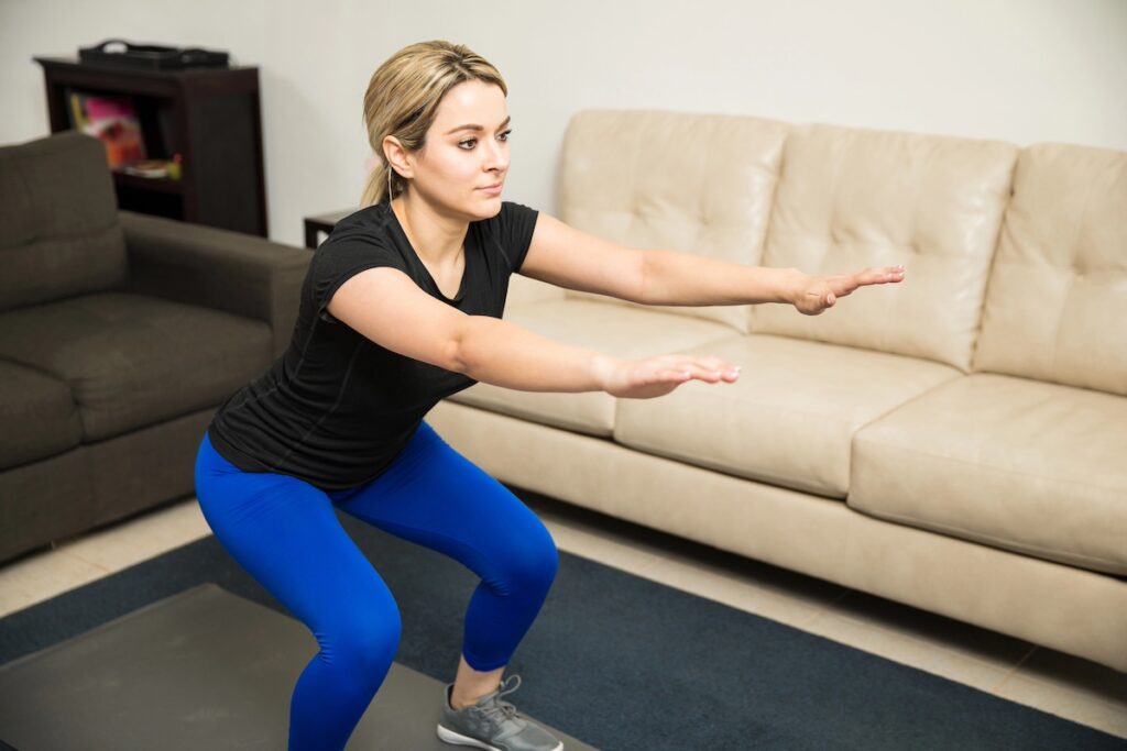 busy mom doing bodyweight squat as part of functional workout routine