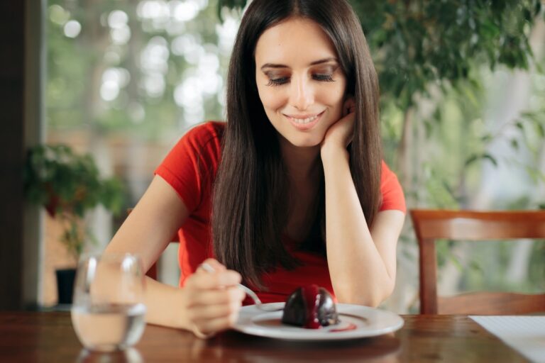 Woman in her 40s eating small chocolate treat instead of cutting sugar to lose weight